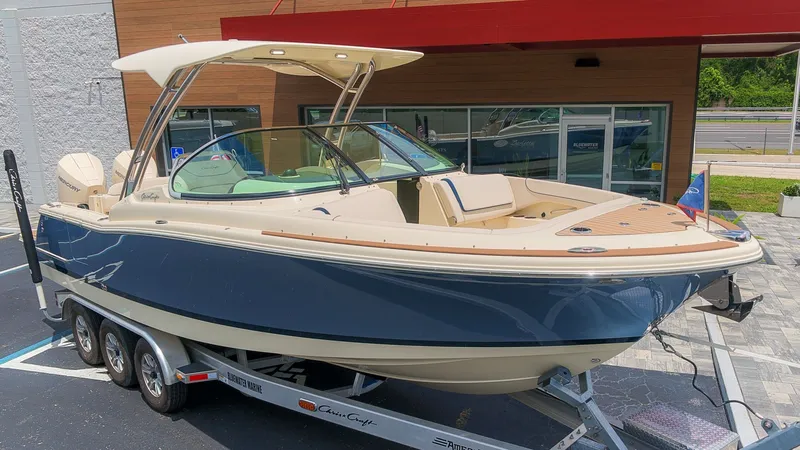 The Image of A 2022 Chris-Craft Calypso 27 on a trailer. The boat features a sleek design with a blue exterior. - 1