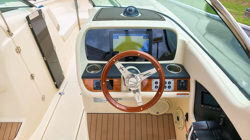 Slide: The Image of The image shows the cockpit of a 2022 Chris-Craft Calypso 27. It features a sleek steering wheel, modern navigation system, and wood accents. - 24