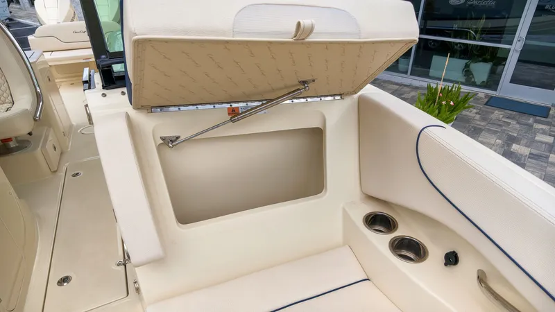 Slide: The Image of The 2022 Chris-Craft Calypso 27 features an open storage compartment with cushioned seating and cup holders. - 19