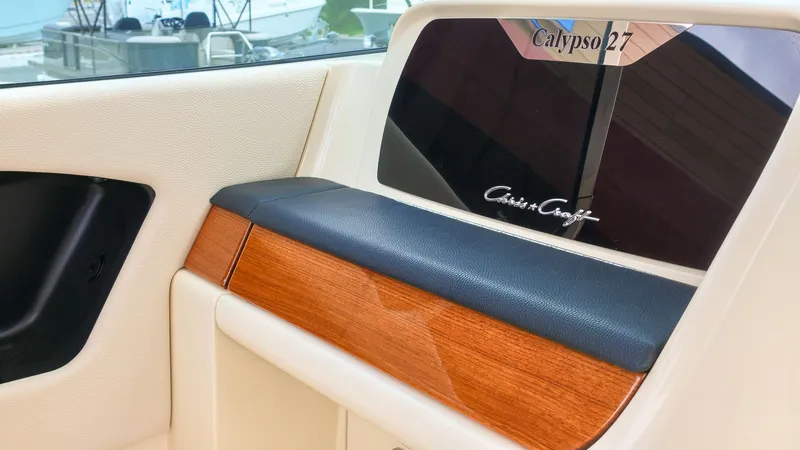 Slide: The Image of Interior view of a 2022 Chris-Craft Calypso 27 with elegant wood and leather accents. - 14