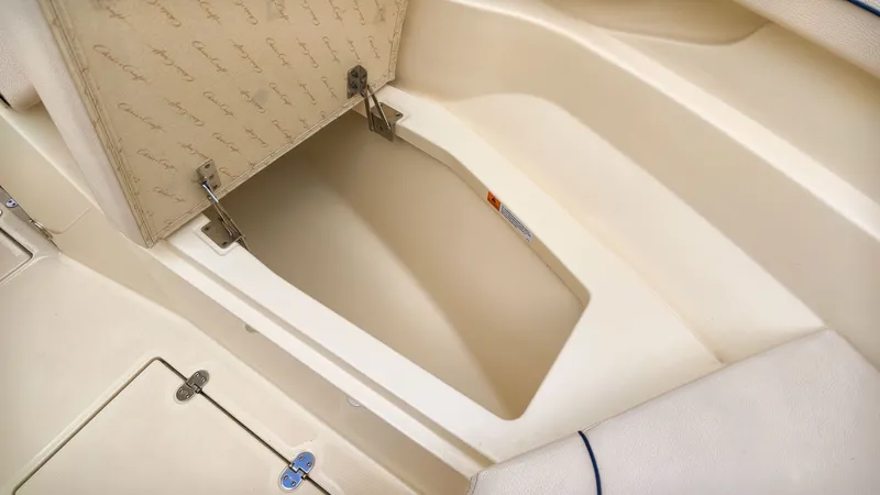 Slide: The Image of An open storage compartment on a 2022 Chris-Craft Calypso 27 boat, featuring a cushioned lid. - 19