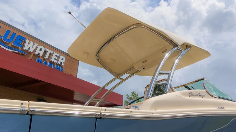 The Image of A 2022 Chris-Craft Calypso 27 with a sleek hardtop, in front of a building labeled "Bluewater Marine." - 1