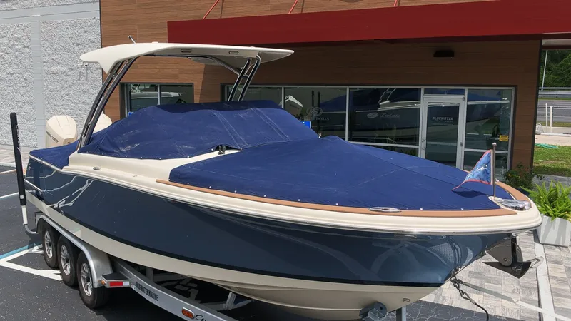 Slide: The Image of A 2022 Chris-Craft Calypso 27 boat on a trailer in front of a modern building. - 29