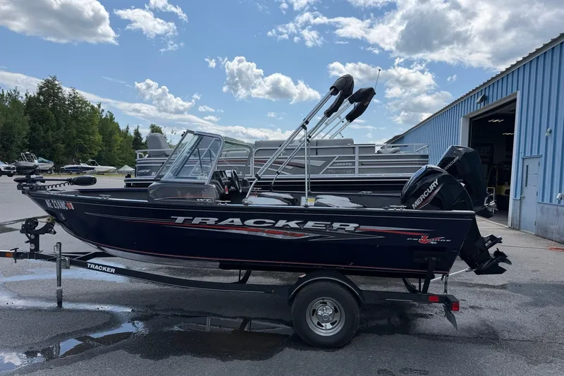 The Image of 2020 Tracker Pro Guide V-16 WT boat on trailer, parked outdoors near blue building. - 0
