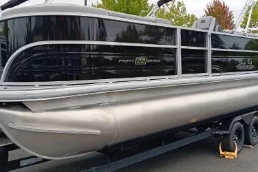 The Image of 2027 Sun Tracker Party Barge 22 DLX pontoon boat on trailer, parked outdoors. - 0