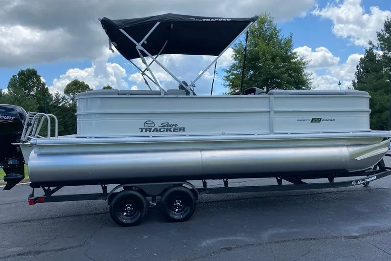 The Image of 2027 Sun Tracker Party Barge 22 DLX pontoon boat on trailer, parked outdoors. - 0