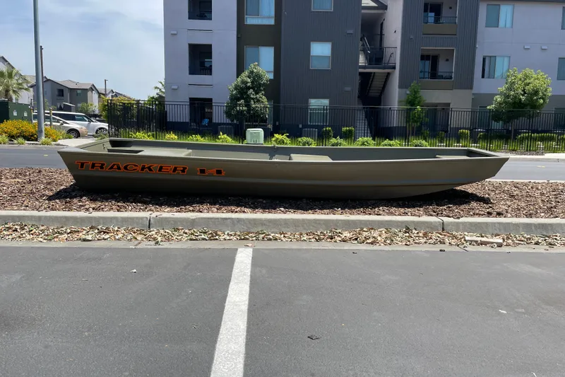 The Image of Tracker Grizzly 14 Jon boat parked outdoors near modern apartment buildings, 2027 model. - 0