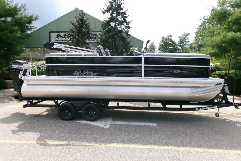 The Image of 2027 Sun Tracker Party Barge 22 DLX pontoon boat on trailer, parked outdoors. - 0