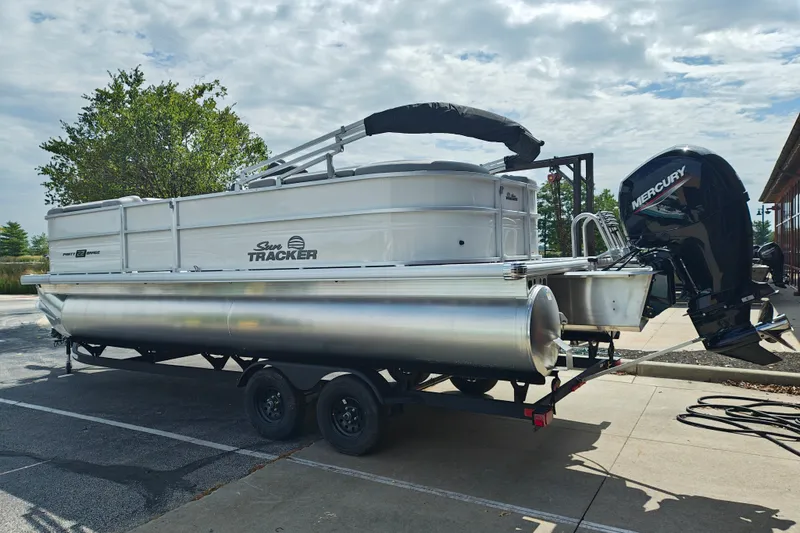The Image of 2027 Sun Tracker Party Barge 22 DLX pontoon boat on trailer, parked outdoors. - 1