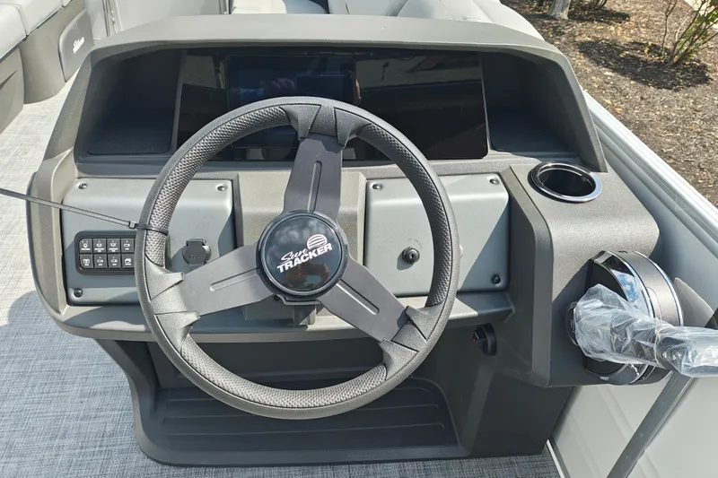 Slide: The Image of Steering console of 2027 Sun Tracker Party Barge 22 DLX with modern controls and cup holder. - 17