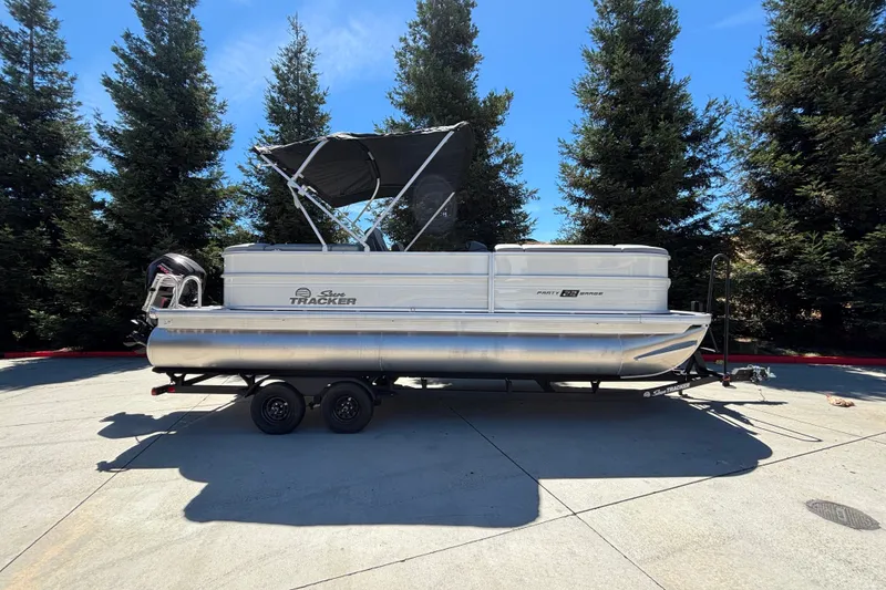 The Image of 2027 Sun Tracker Party Barge 22 DLX pontoon boat on trailer, parked outdoors. - 0
