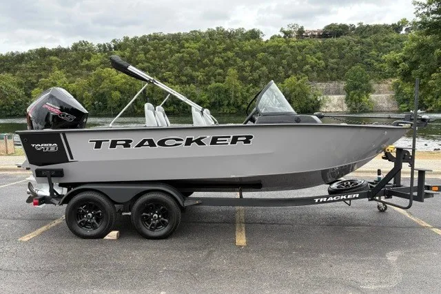 The Image of 2027 Tracker Targa V-18 WT boat on trailer, parked near a scenic river. - 0