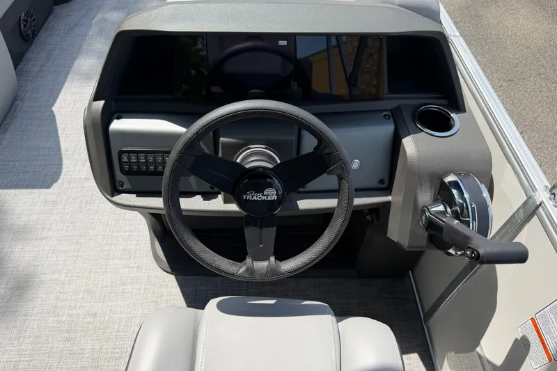 Slide: The Image of 2027 Sun Tracker Party Barge 22 DLX steering console with controls and cup holder. - 16