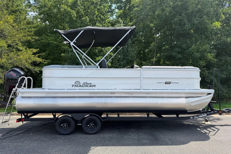 The Image of 2027 Sun Tracker Party Barge 22 DLX pontoon boat on trailer, parked outdoors. - 0