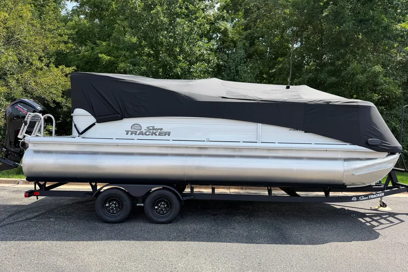 Slide: The Image of 2027 Sun Tracker Party Barge 22 DLX pontoon boat covered on trailer, parked outdoors. - 22