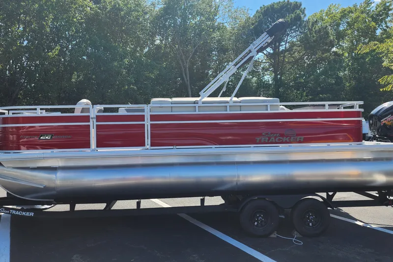 The Image of 2027 Sun Tracker Fishin' Barge 22 DLX pontoon boat on trailer, parked outdoors. - 0