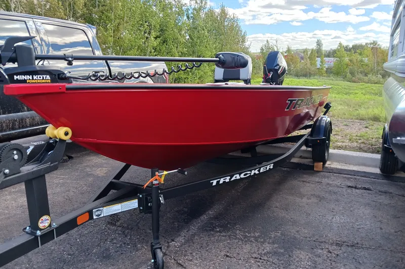 The Image of Red 2027 Tracker Super Guide V-16 T boat on trailer, parked outdoors. - 0