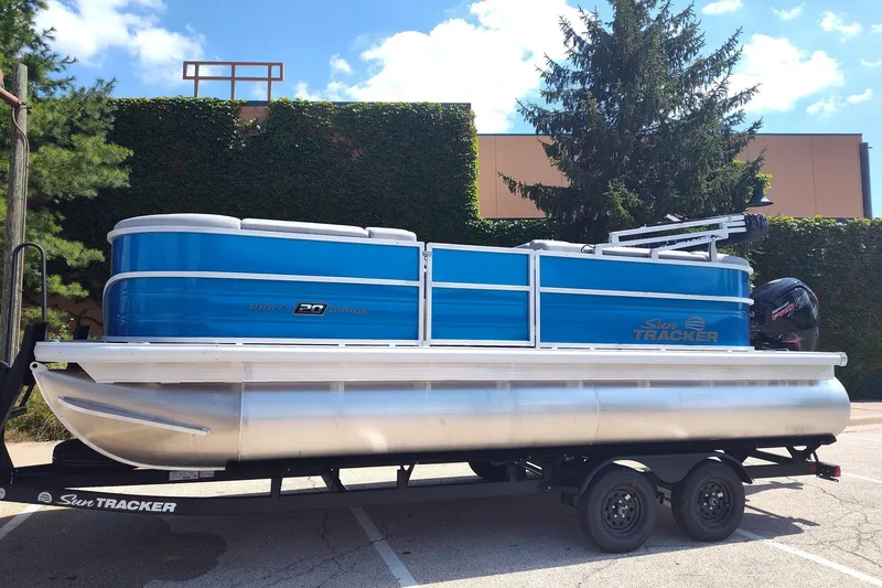The Image of 2027 Sun Tracker Party Barge 20 DLX pontoon boat on trailer, parked outdoors. - 0