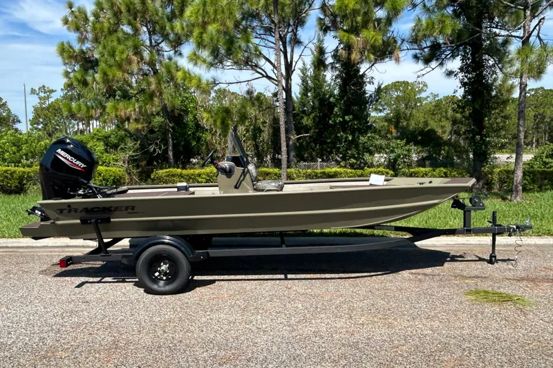 The Image of 2027 Tracker Grizzly 1860 CC boat on trailer, parked outdoors near trees. - 0