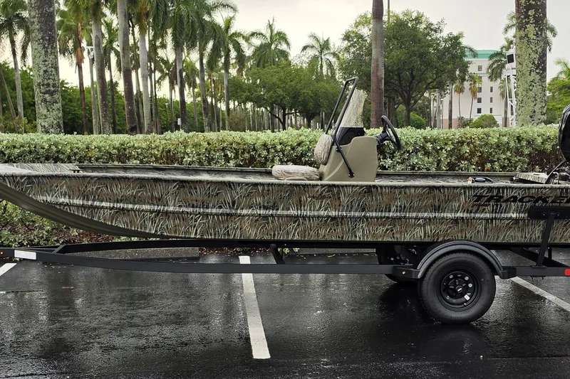 The Image of 2027 Tracker Grizzly 1860 CC boat with camouflage design on a trailer in a parking lot. - 0