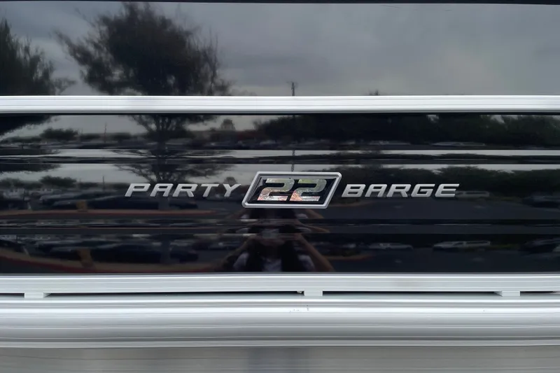 Slide: The Image of 2027 Sun Tracker Party Barge 22 DLX logo on sleek black surface. - 25