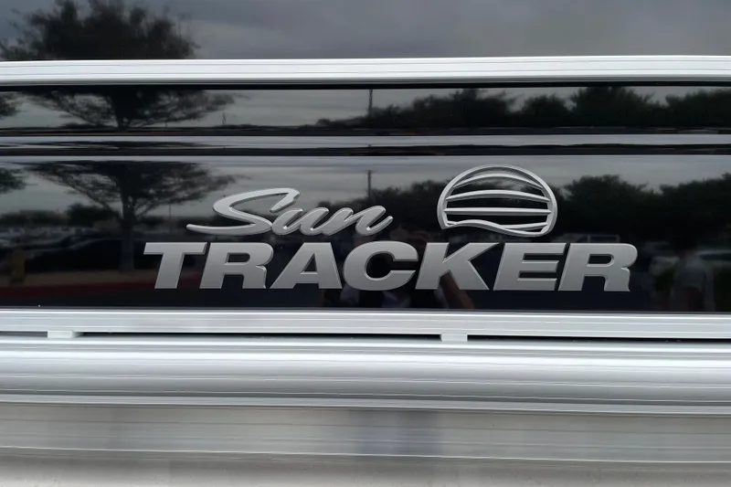 Slide: The Image of Sun Tracker Party Barge 22 DLX 2027 logo on sleek black surface. - 26