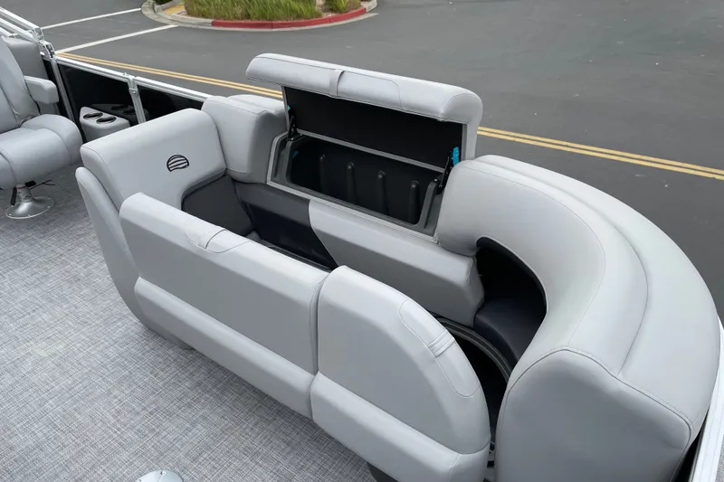 Slide: The Image of 2027 Sun Tracker Party Barge 22 DLX with open storage compartment and gray seating. - 15