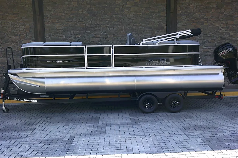 The Image of 2027 Sun Tracker Party Barge 22 DLX pontoon boat on trailer, parked on paved surface. - 0