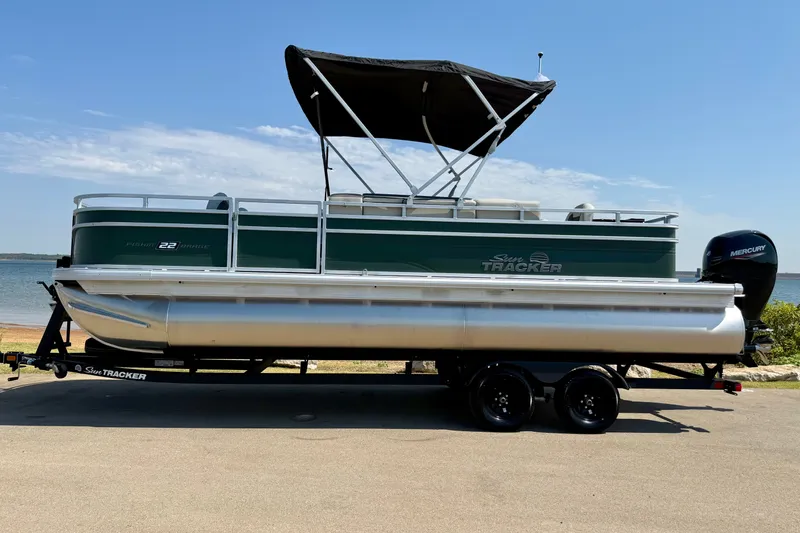 Slide: The Image of 2027 Sun Tracker Fishin' Barge 22 DLX pontoon boat on trailer by the water. - 15