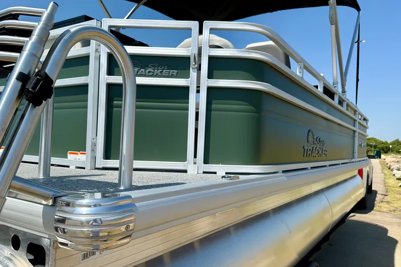 Slide: The Image of 2027 Sun Tracker Fishin' Barge 22 DLX pontoon boat, green exterior, docked outdoors. - 17