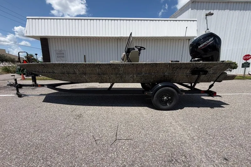 The Image of 2027 Tracker Grizzly 1860 CC boat on trailer, parked outdoors under a clear sky. - 0