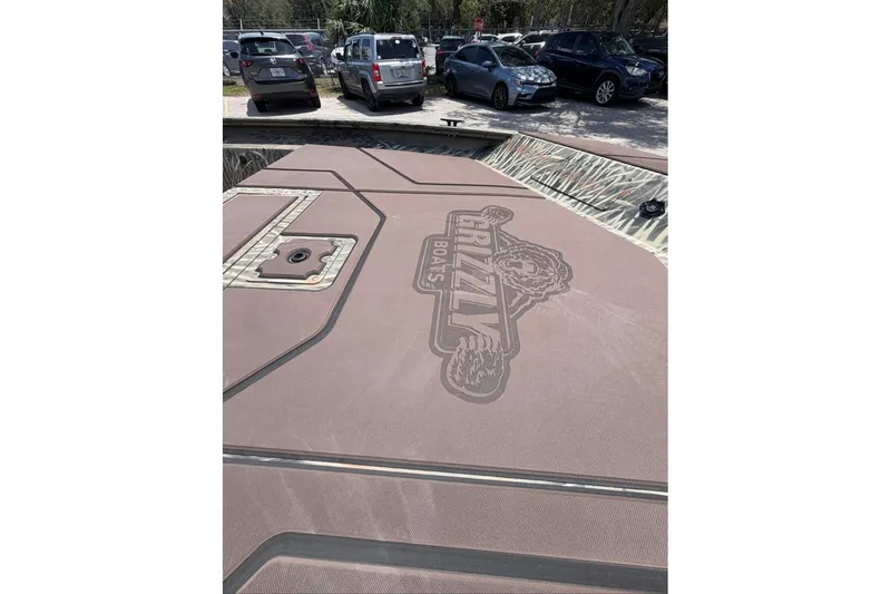Slide: The Image of 2027 Tracker Grizzly 1860 CC boat deck with logo, parked in a lot. - 72