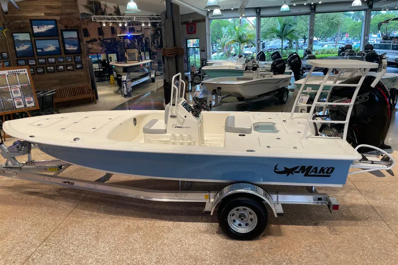 Slide: The Image of 2026 Mako 18 Pro Skiff boat displayed in a showroom, featuring sleek design and modern features. - 2