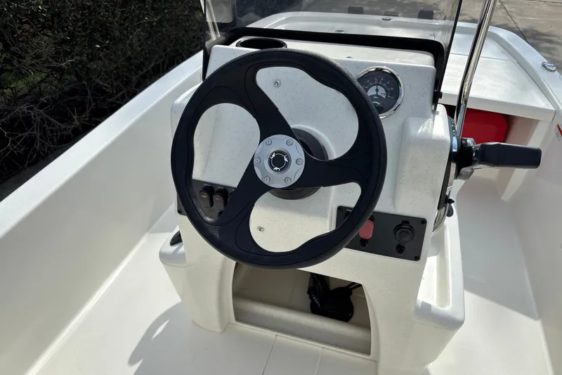 Slide: The Image of Steering console of 2026 Mako Pro Skiff 13 CC boat, featuring a black wheel and gauges. - 12