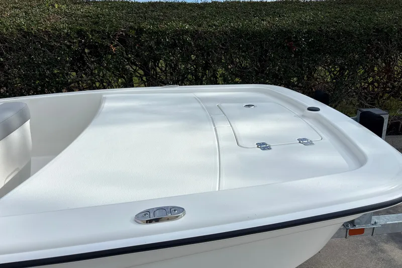 Slide: The Image of 2026 Mako Pro Skiff 13 CC boat deck with storage compartment, surrounded by greenery. - 6