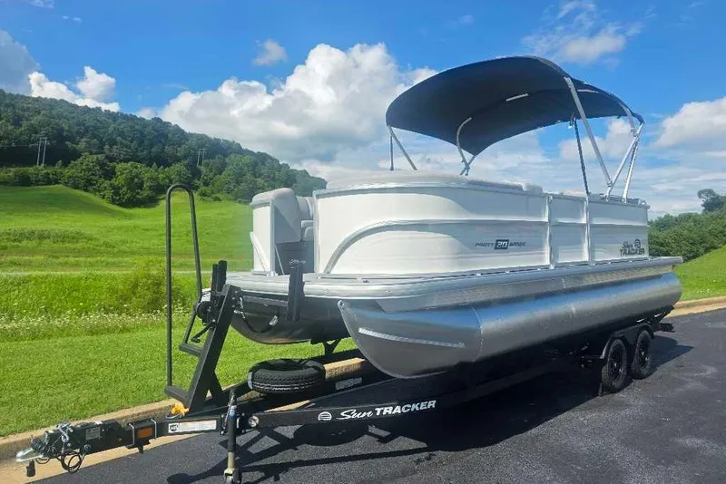 The Image of 2027 Sun Tracker Party Barge 20 DLX pontoon boat on trailer, scenic background. - 0