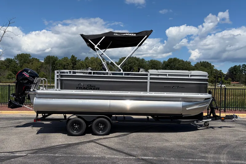 The Image of 2027 Sun Tracker SportFish 20 DLX pontoon boat on trailer, parked outdoors. - 0