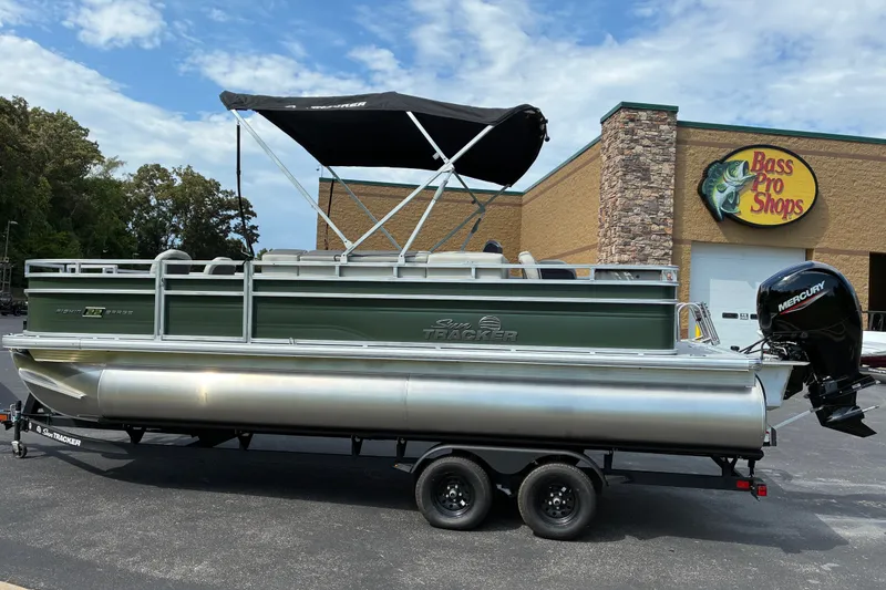 The Image of 2027 Sun Tracker Fishin' Barge 22 DLX pontoon boat at Bass Pro Shops parking lot. - 0