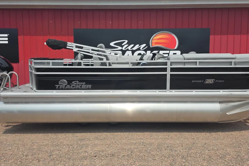 The Image of 2027 Sun Tracker SportFish 20 DLX pontoon boat displayed against a red wall. - 0
