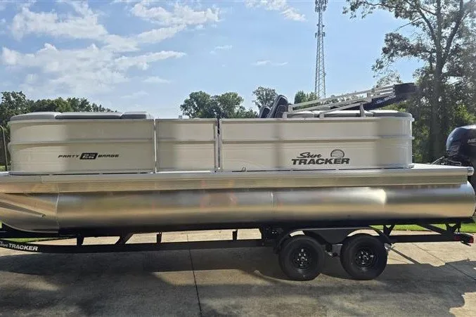 The Image of 2027 Sun Tracker Party Barge 22 DLX pontoon boat on trailer, parked outdoors. - 0