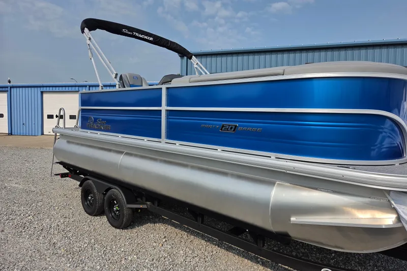 The Image of 2027 Sun Tracker Party Barge 20 DLX pontoon boat with blue exterior on trailer. - 0