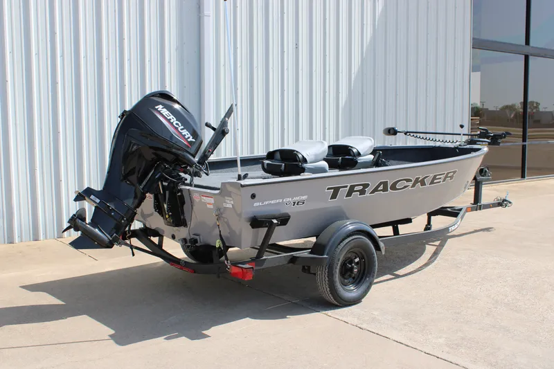 Slide: The Image of A gray Tracker Super Guide V-16 T boat from 2027 on a trailer in front of a building. - 13