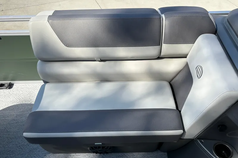 Slide: The Image of 2027 Sun Tracker Fishin' Barge 22 DLX boat seat, gray and black upholstery, outdoor setting. - 28