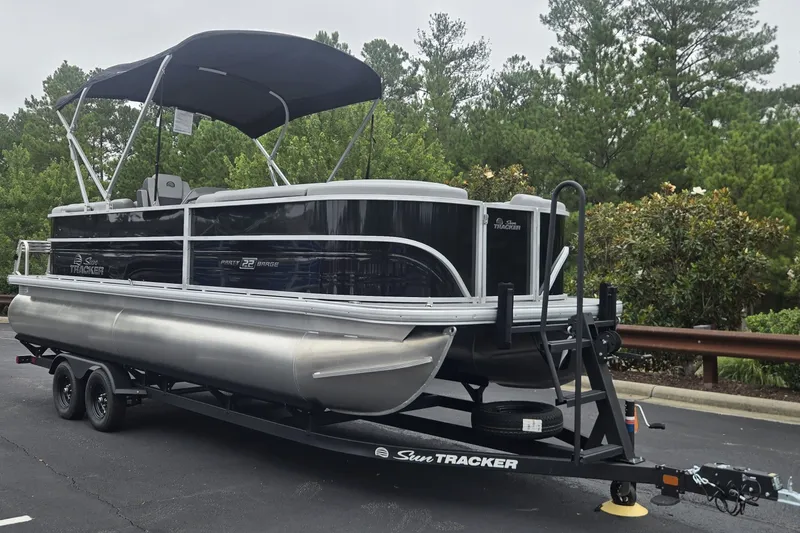 The Image of 2027 Sun Tracker Party Barge 22 DLX pontoon boat on trailer, parked outdoors. - 0