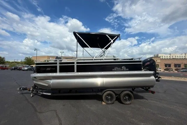 The Image of 2027 Sun Tracker SportFish 20 DLX pontoon boat with canopy on trailer, parked outdoors. - 0