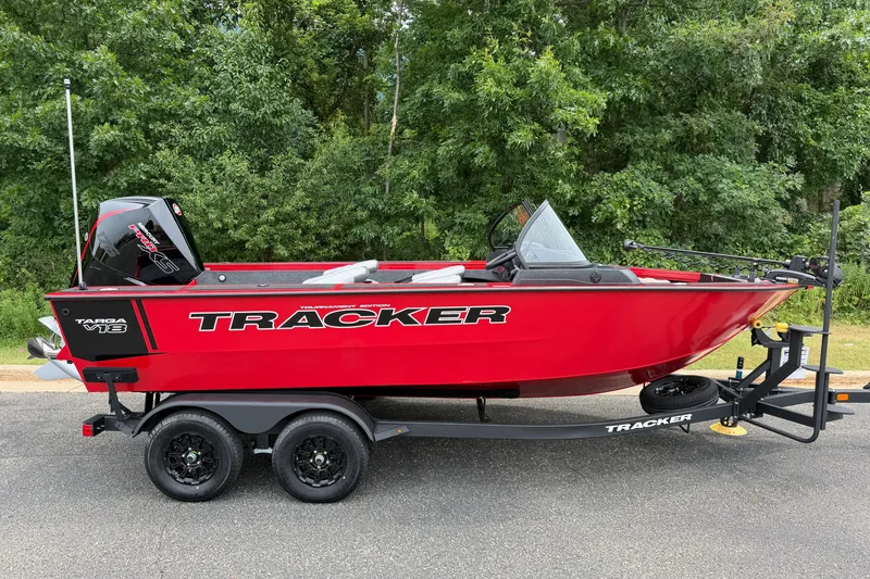 The Image of Red 2027 Tracker Targa V-18 WT boat on trailer, parked near lush greenery. - 0