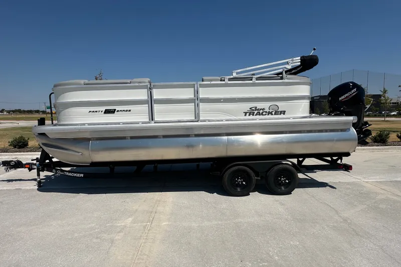 The Image of 2027 Sun Tracker Party Barge 20 DLX pontoon boat on trailer, parked outdoors. - 1