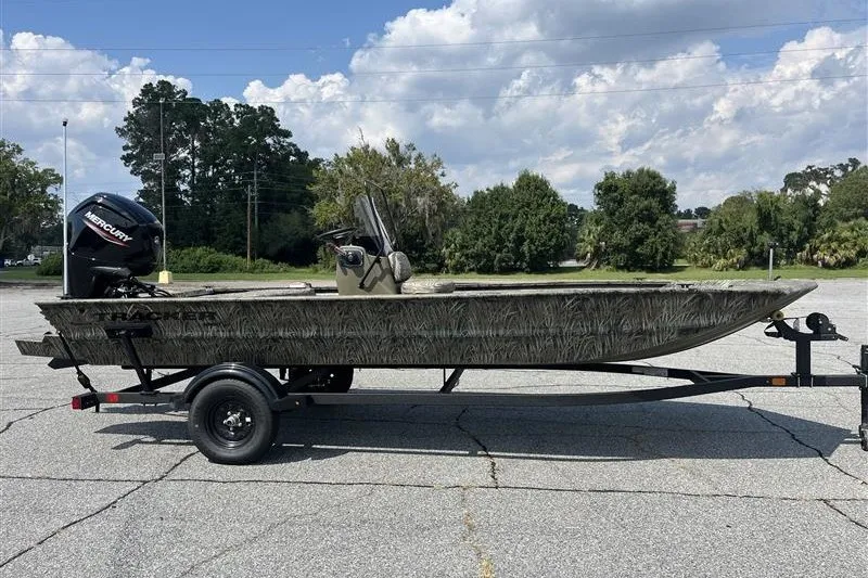 The Image of 2027 Tracker Grizzly 1860 CC boat on trailer, parked outdoors under cloudy sky. - 0