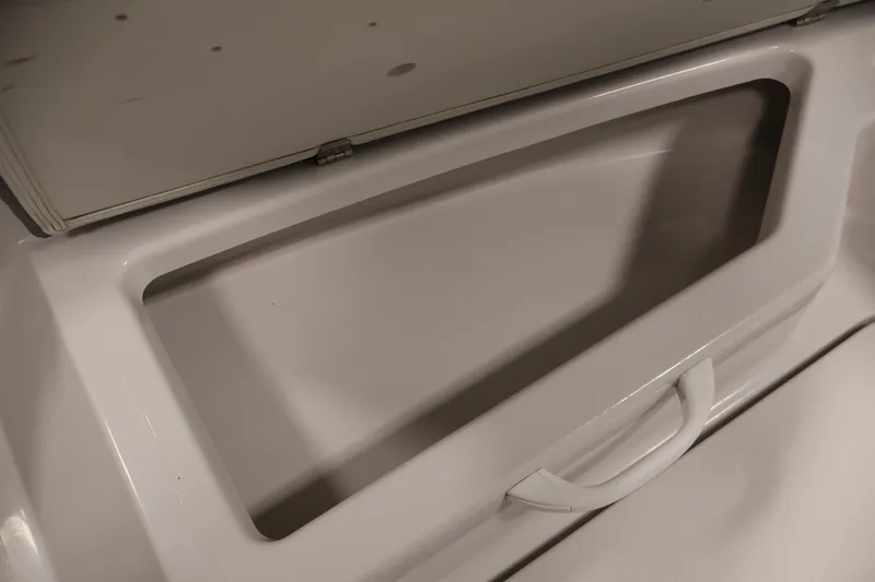 Slide: The Image of Storage compartment of a 2019 Scarab 165 G boat, featuring a white handle. - 13