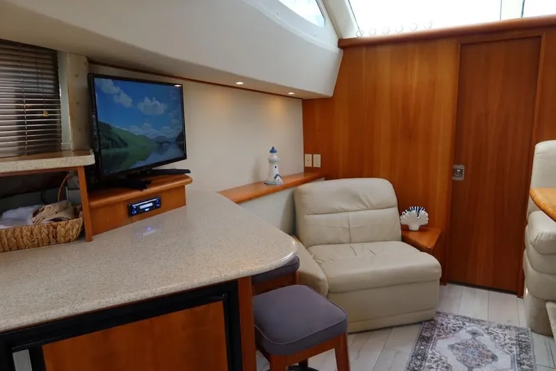 Slide: The Image of Interior of 2000 Silverton 330 Sport Bridge with TV, seating, and wooden accents. - 10